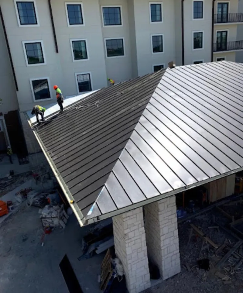 Crew installing standing seam metal roof panels on a commercial project in South Ogden